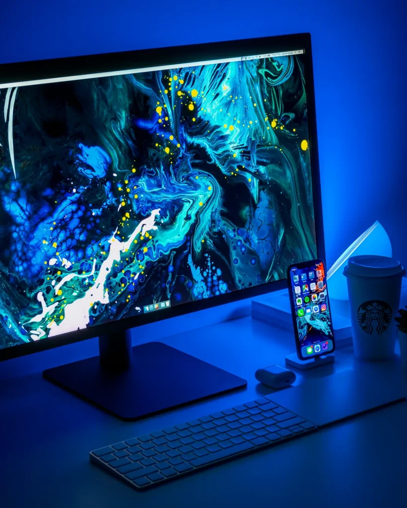 A blue-lit desk with a monitor, keyboard and phone