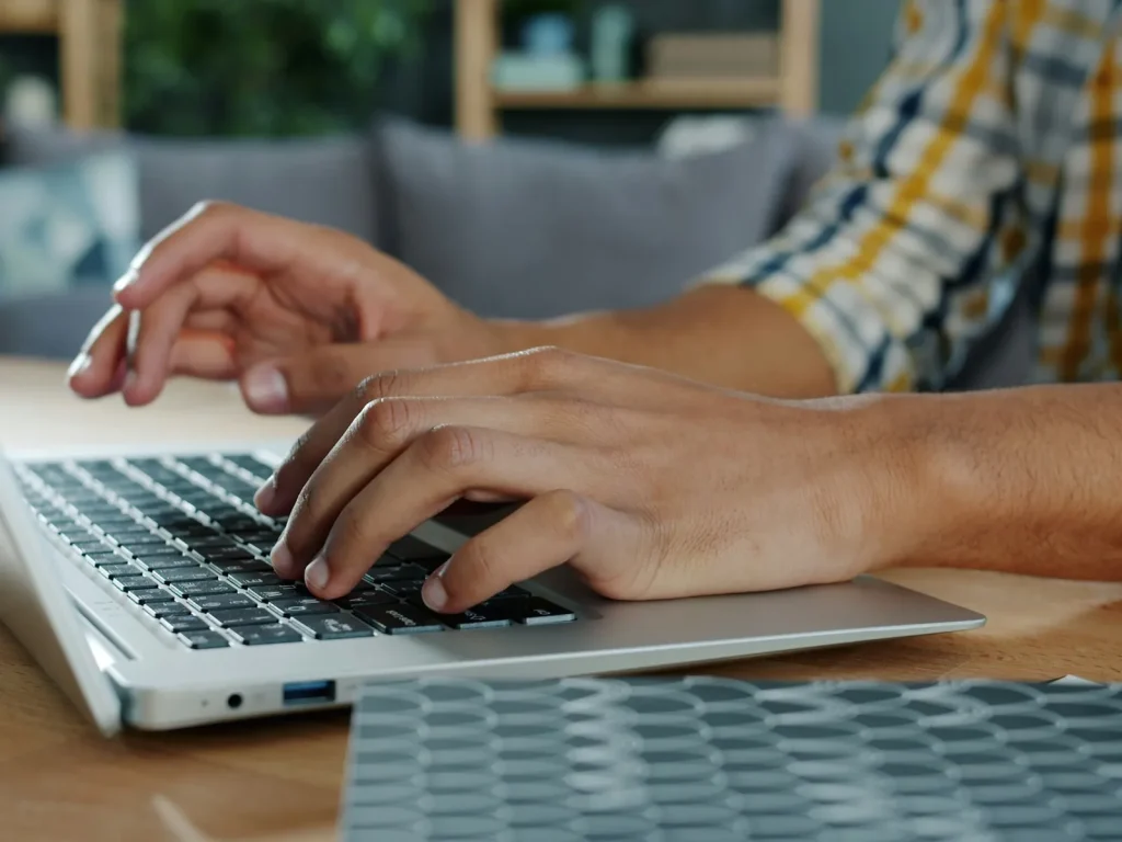 Hands typing on a laptop at a wooden desk